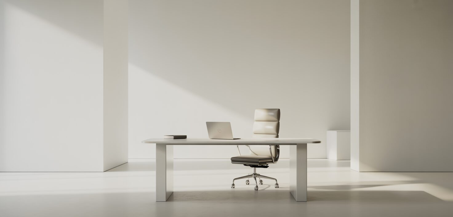Ett rent, minimalistiskt kontorslandskap med vita skrivbord och en anställd som sitter vid ett av dem, omgiven av massor av naturligt ljus.